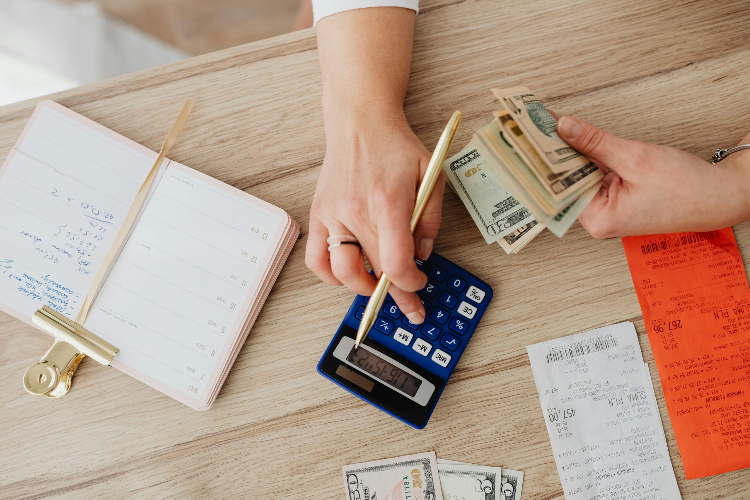 Person Holding Paper Bills while Using a Calculator